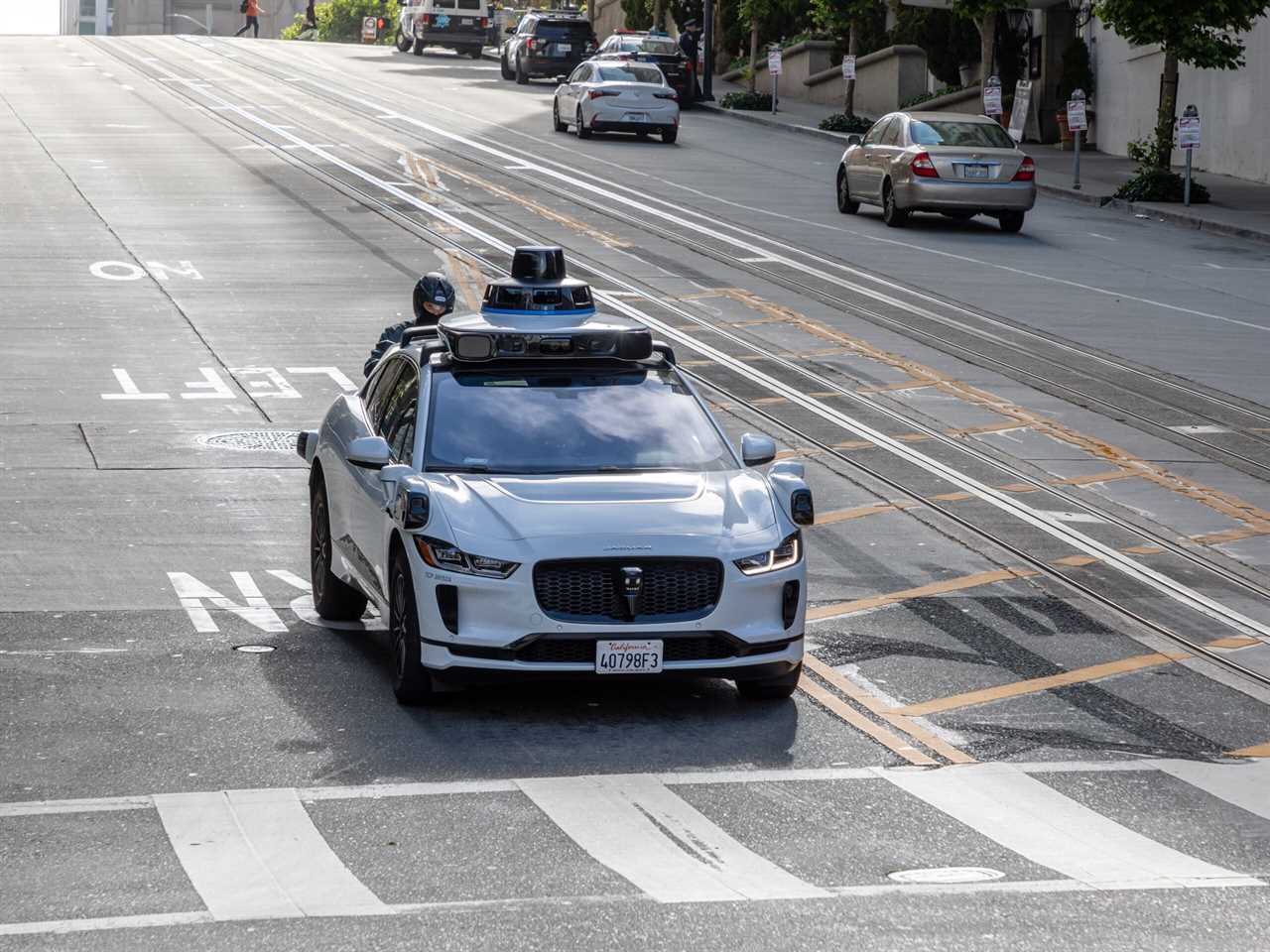 Autonomous electric vehicle equipped with sensors navigating a city street, showcasing advancements in self-driving technology.