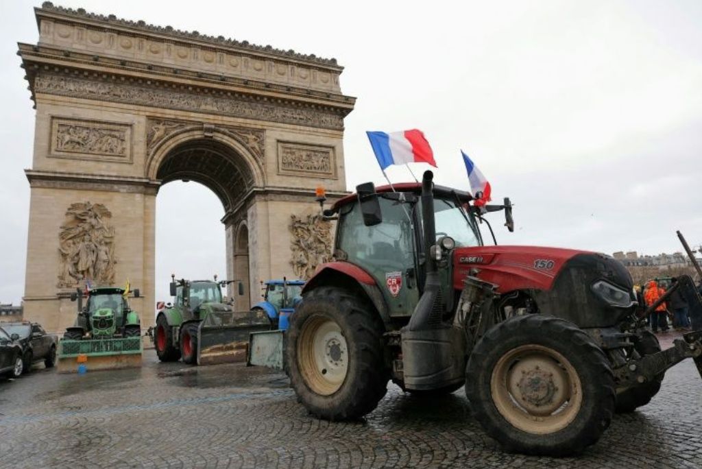 Tractors with French flags are parked in front of the Arc de Triomphe in Paris during a protest event.