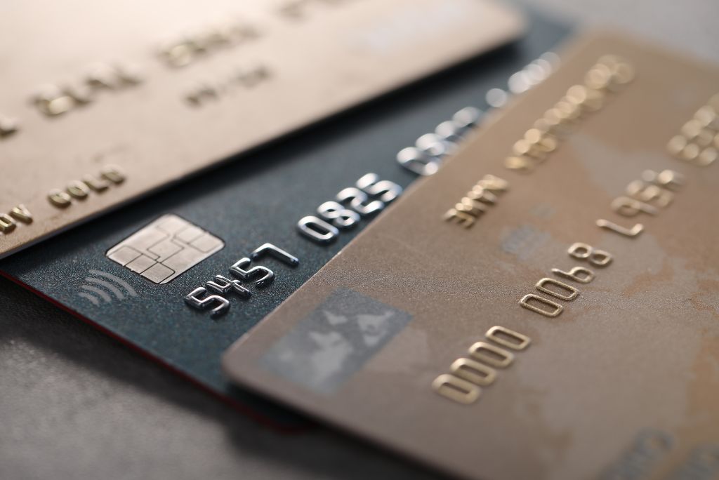 Close-up of various credit cards, showcasing contactless payment features and distinct designs on a textured surface.