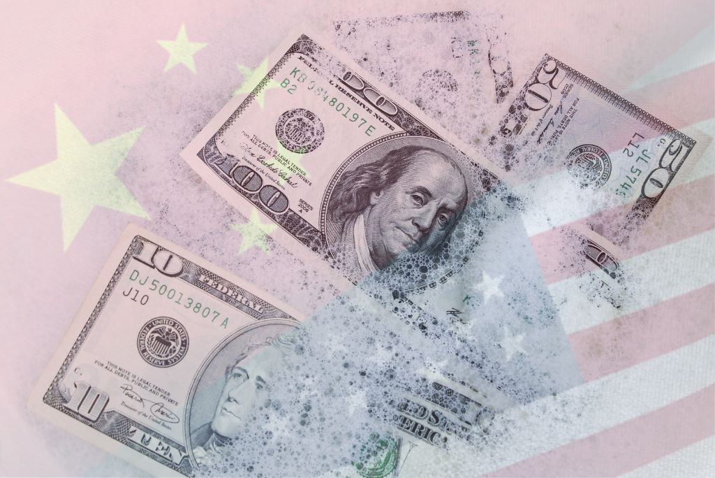 U.S. dollar bills submerged in bubbles against a backdrop of the American and Chinese flags, symbolizing international finance and trade tensions.