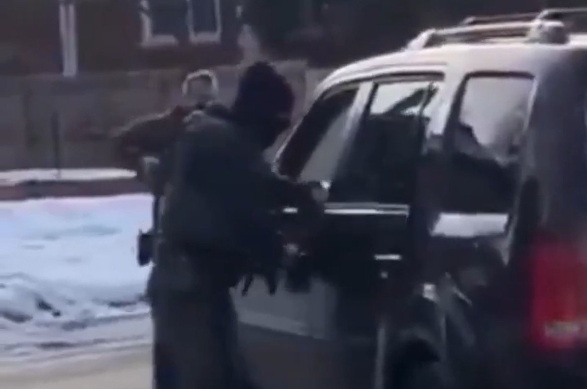 Law enforcement officer approaching a vehicle during a roadside stop in a snowy residential area.