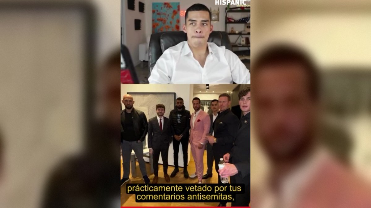 Group of men in formal attire posing for a photo, with one man sitting at a desk in a white shirt, conveying a serious expression.