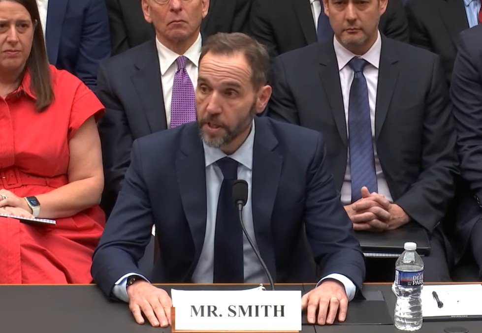 Mr. Smith testifies before Congress, discussing key issues with a panel of officials seated behind him.