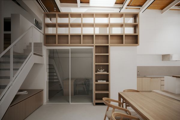 An office/flex space is tucked beneath a wall of built-in shelving.