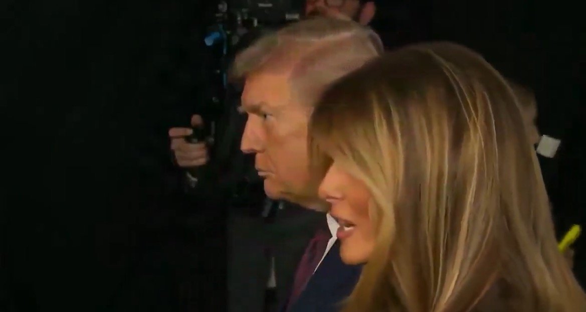 Donald Trump and Melania Trump are seen walking together, with cameras capturing their appearance at a public event.
