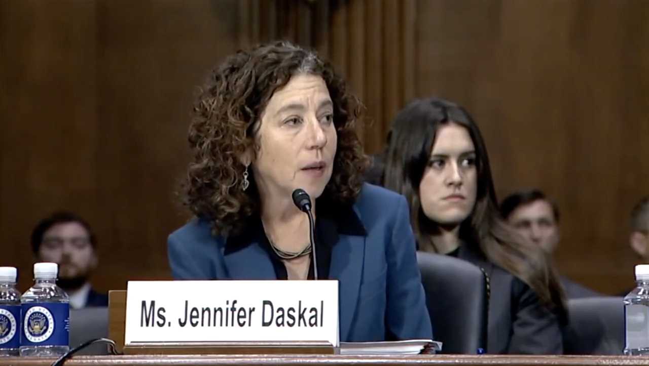 Ms. Jennifer Daskal testifies during a Senate hearing, discussing key issues with an attentive audience in the background.