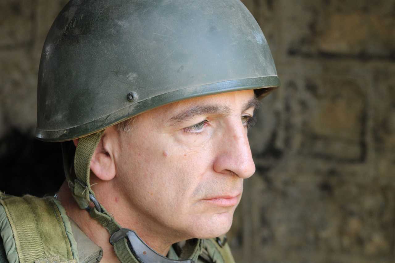 Portrait of a soldier wearing a military helmet, showcasing a serious expression against a textured background, emphasizing themes of duty and resilience.