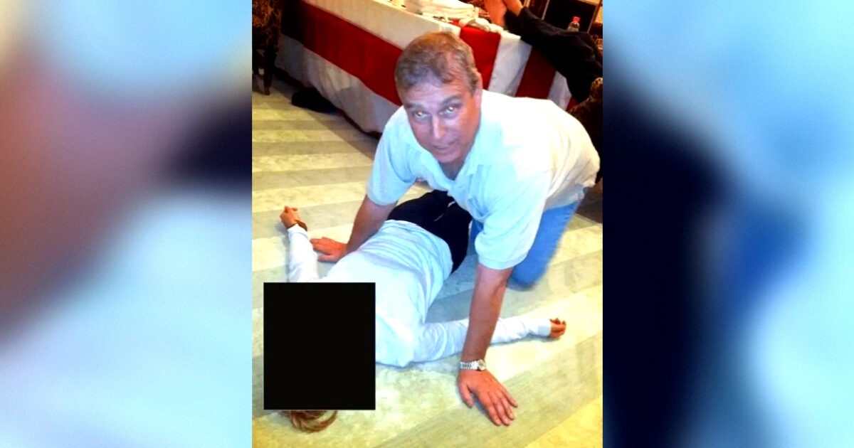 A man performs a physical maneuver on a person lying on the floor in a domestic setting.