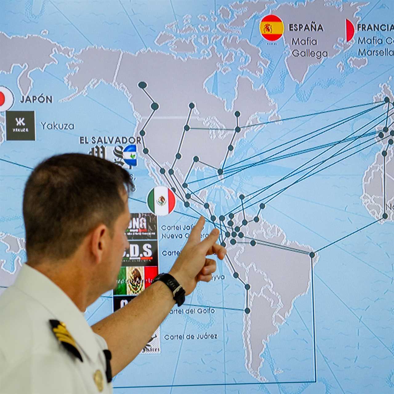 man in naval uniform pointing at a map
