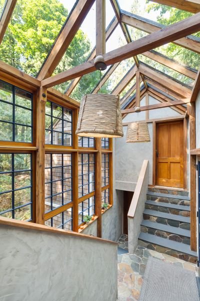 A double-height, glass-paneled foyer connects the common areas to the bedrooms.