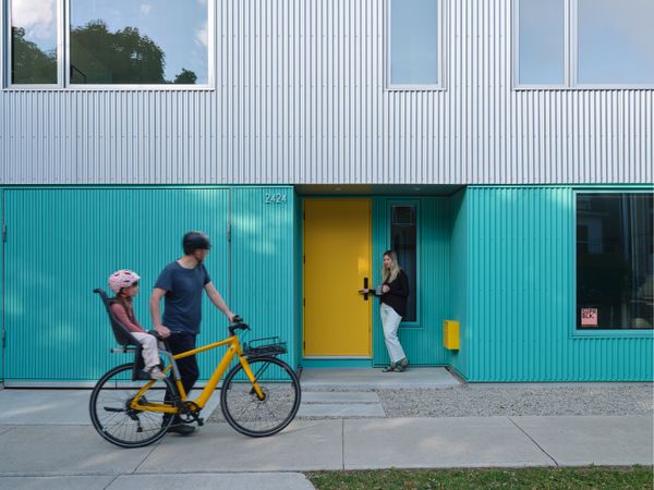 A turquoise recessed door leads to the town house, while a yellow recessed door is a sunny signifier of the family’s main entrance.