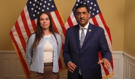 Two individuals standing in front of American flags, engaged in conversation, highlighting a political or community event.