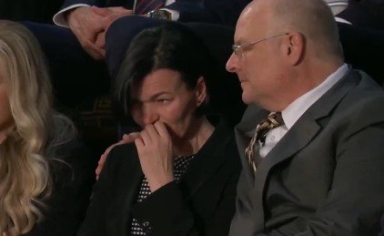 Emotional moment captured at a public event, featuring a woman visibly distressed, sitting next to a supportive man.