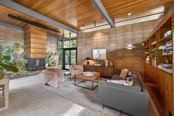 Many of the original finishes have been preserved, including terrazzo slab floors, custom millwork, unpainted basalite walls, warm wood paneling, and two cantilevered fireplaces with copper hoods.
