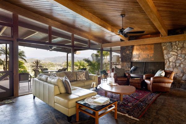 The home features a low-slung roof, redwood structure, and built-in stone fireplace.