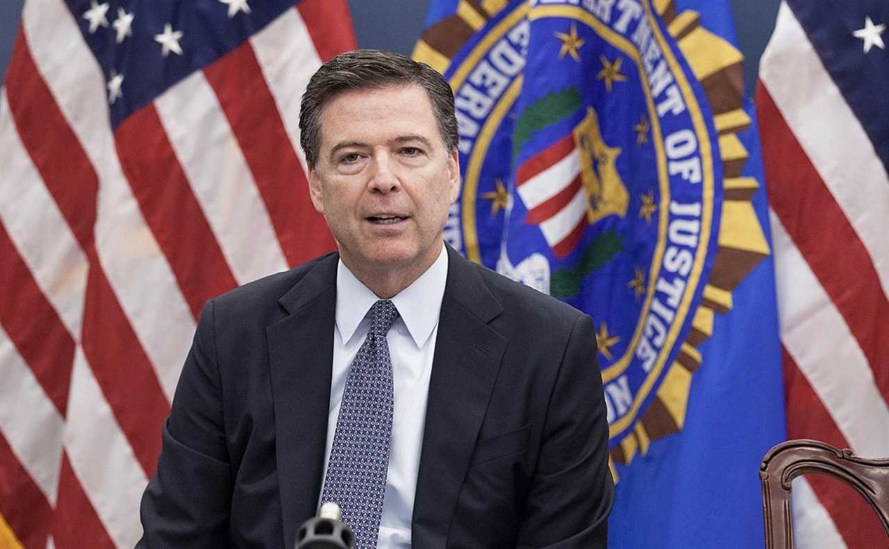 James Comey speaking at a press conference, with the FBI seal and American flags in the background.