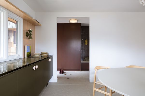 The dining room features a built-in bar with a slatted maple backsplash that nods to the house’s original paneled walls.