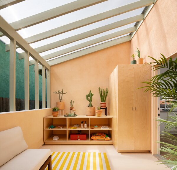 The sunroom in the ADU boasts a clear polycarbonate  ceiling with millwork adding storage and concealing the washer-dryer.