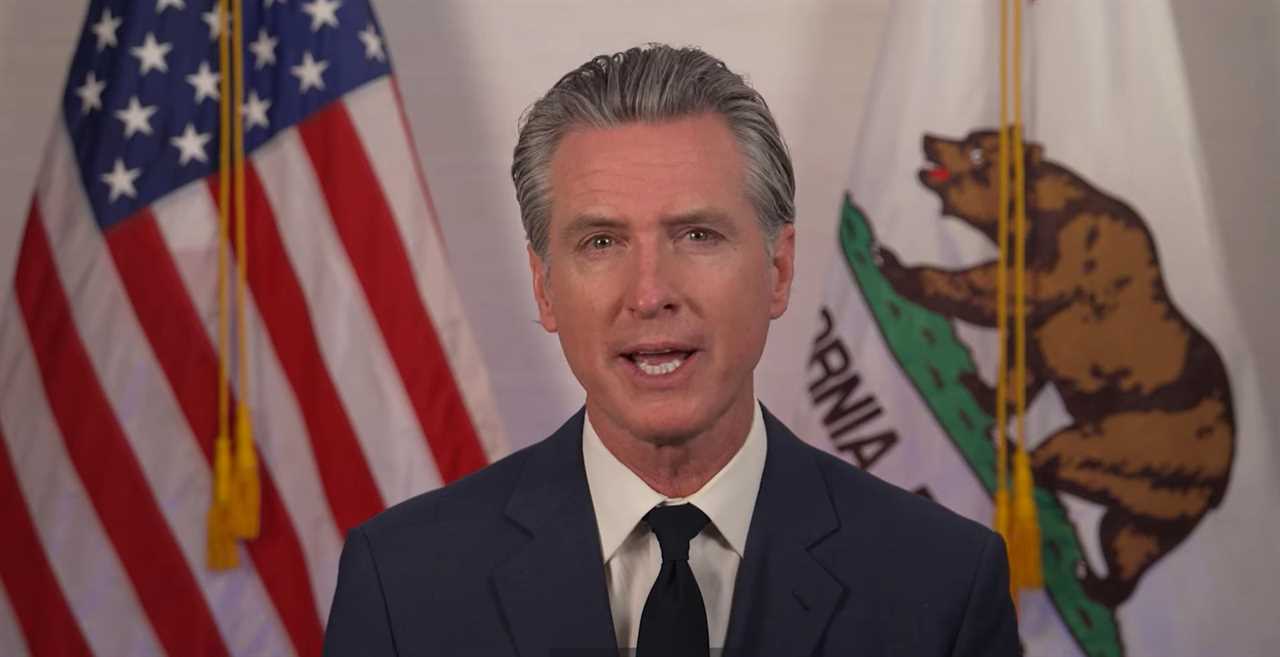 California Governor speaking in front of the American and California flags, addressing key state issues in a formal setting.
