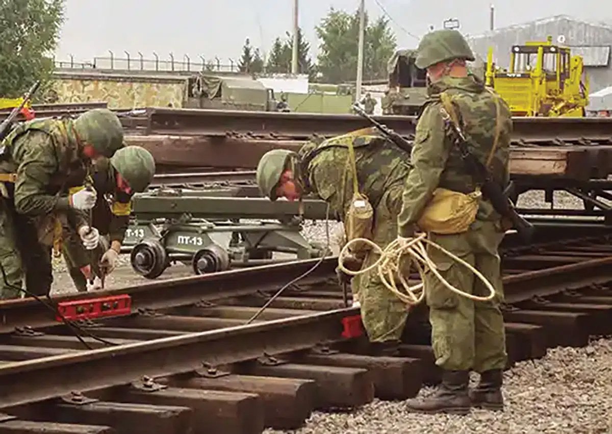 Soldiers inspecting and repairing railway tracks, demonstrating military operations and maintenance in a training environment.