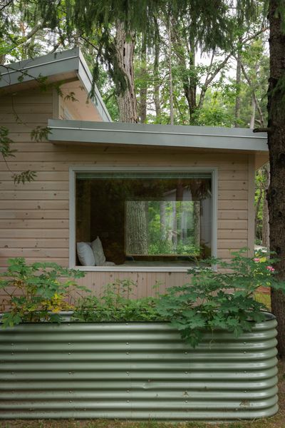 Expansive energy-efficient windows give the feeling of sleeping outdoors amongst the trees. Corrugated metal planters offset the pine and lend a modernist quality.