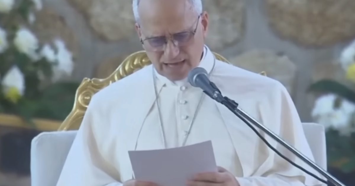 Pope Francis delivers a speech while holding a paper and speaking into a microphone during a public event.