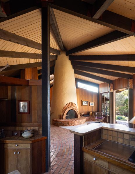 The fireplace is housed in a masonry tower off which the roof structure extends outward, sloping towards the earth.