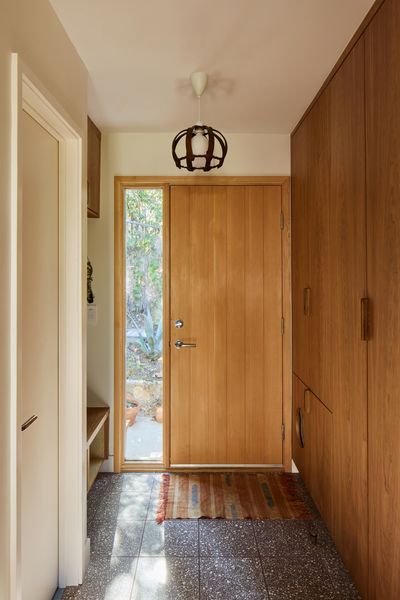 The new entrance was moved toward the south of the house to create a larger kitchen and bathroom and place all of the private spaces toward the south. Zander came up with the idea to place a litter box and fan within the custom cherry millwork. A T.M. Cobb front door and Zia terrazzo tile in Alexander surround it.