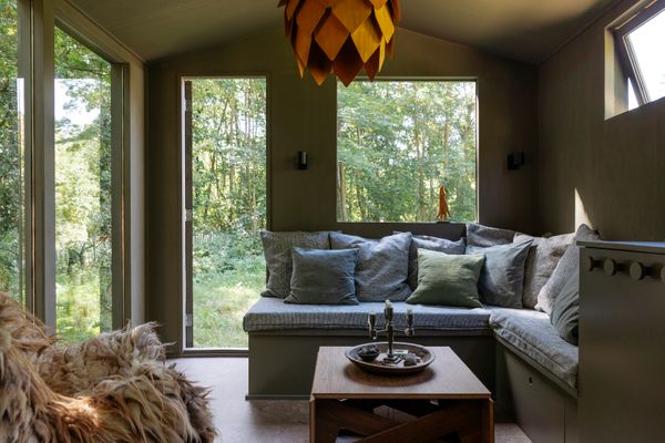 The shared living and dining space has a built-in seating area that can be converted into a guest bed. The coffee table can be raised into a larger dining surface, and there's storage beneath the seating.