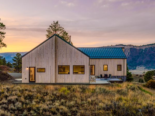 The home’s two pitched volumes—one containing the great room and primary suite, and the other housing guest quarters and a kids’ bedroom—converge in a nearly-perpendicular configuration.
