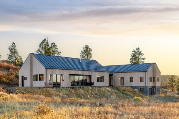 In bright daylight conditions, the home’s standing seam metal roof appears visually light—complementing the tones of the charred wood cladding. A metal retaining wall is an extension of the home’s metal siding, wrapping in a ribbon-like fashion around the lower perimeter.