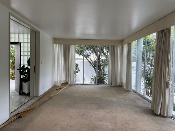 Before: The living room had fixed glass panels, carpet, and heavy drapes.
