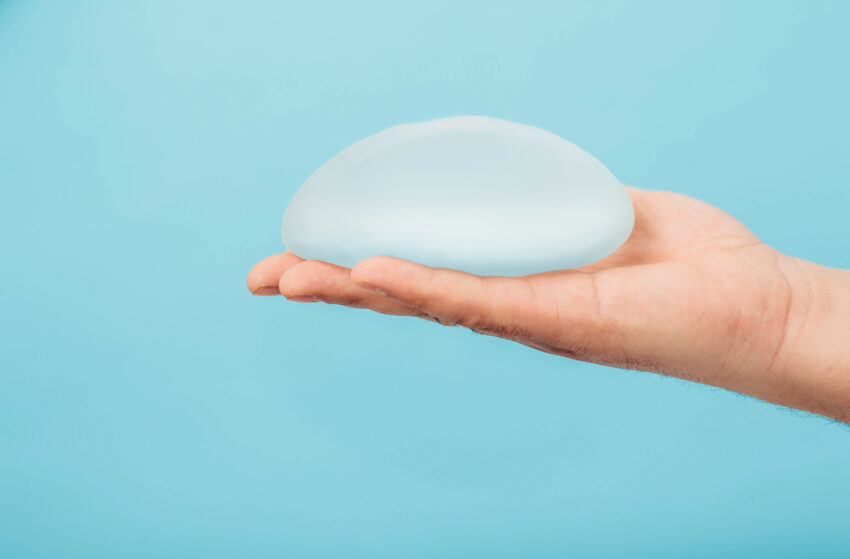 A smooth, translucent silicone breast implant held against a soft blue background, showcasing the quality of implants used in breast augmentation procedures at Cosmedica Aesthetic in Istanbul.