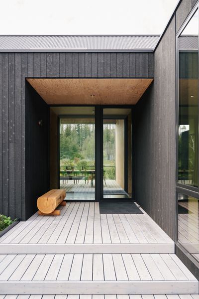 The home is composed of two parallel wings—one housing the main living space, kitchen, and primary bedroom suite; and the other containing the family room, bunk room, and garage.