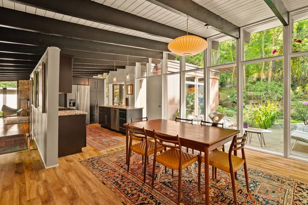 Ten-foot walls of glass bring the surrounding gardens into the dining area, while original exposed Douglas fir beams and original tongue-and-groove ceilings run throughout the main living spaces.