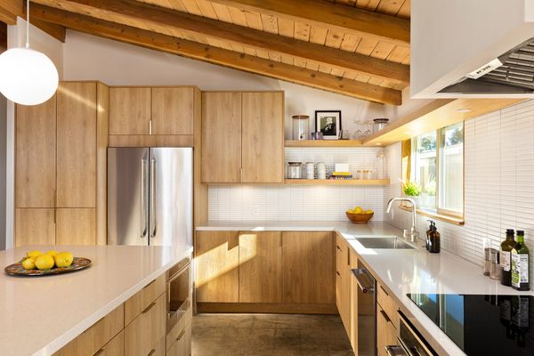 The updated kitchen features custom white oak cabinetry, quartz countertops, and stainless-steel appliances.
