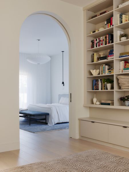 The primary bedroom features the floor-to-ceiling drapes that are a staple throughout the new renovation, highlighting the home's tall ceilings.