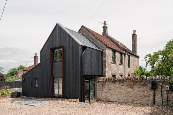 An dark wood addition extends froms a traditional Somerset rubble-stone cottage.
