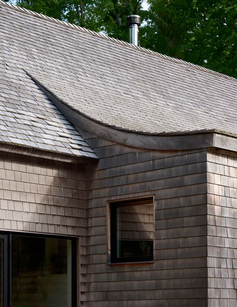 One distinctive feature of the home’s restrained exterior is a catslide roof that stretches away from the main gable. The architects built a kitchen under this geometry, and left the curve visible indoors.