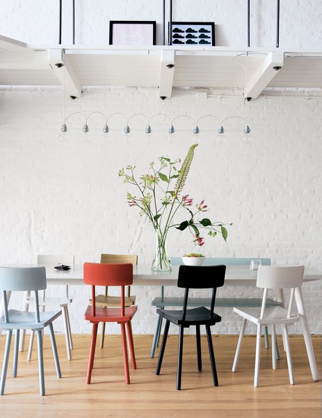 Piet Hein Eek's wooden chairs add a touch of color to the monochromatic Amsterdram apartment of Hunter Hindman and Shelby Carr.
